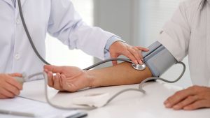 Doctor checking patients blood pressure on right arm